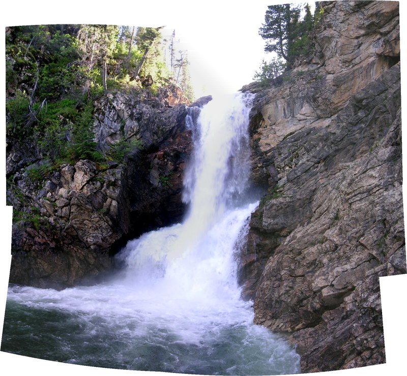 Running Eagle Falls with water emerging from a mid-cliff opening in a forested canyon