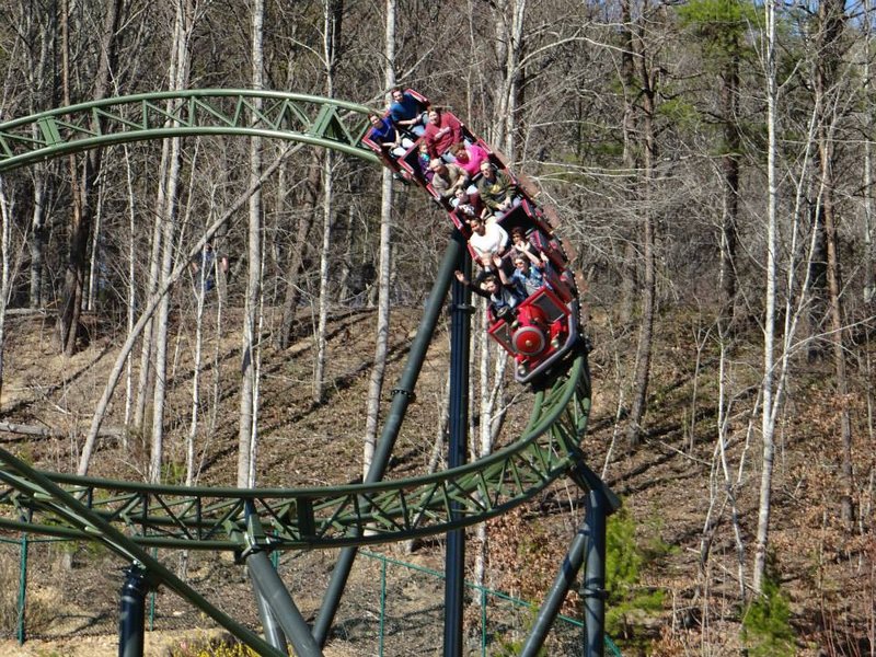 Roller coaster train winding through wooded Smoky Mountains foothills at Dollywood