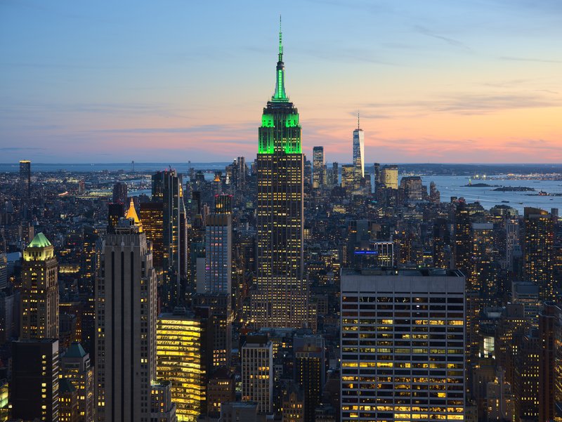 New York skyline at dusk with the Empire State Building's illuminated Art Deco spire rising above Midtown