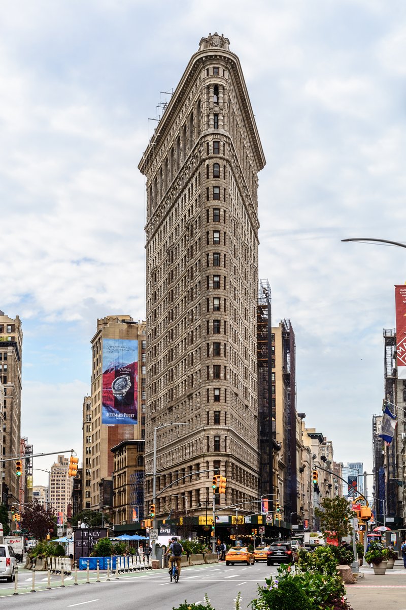 The triangular Flatiron Building rising over a Manhattan avenue intersection