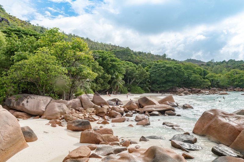 Granite boulders and forested hills framing the white-sand bay at Anse Lazio, Praslin