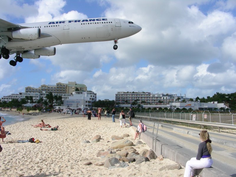 An airliner passing at extremely low altitude over sunbathers on the sand at Maho Beach, Sint Maarten