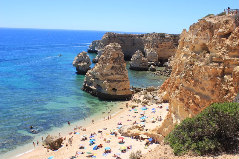 Ochre limestone sea stacks and arches framing the sand at Praia da Marinha, Algarve