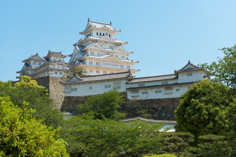 White plastered walls and layered roofs of Himeji Castle on its hilltop