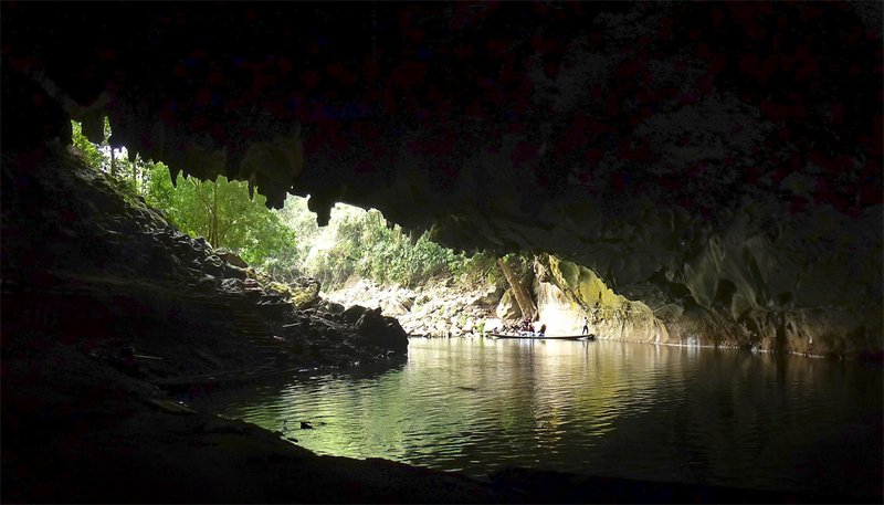 Longtail boat entering the river cave passage of Kong Lor through the limestone karst