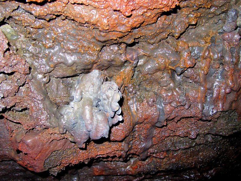 Colorful mineral-stained lava tube ceiling with dripstone formations inside Leiðarendi cave
