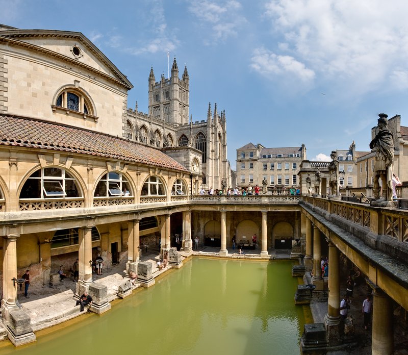 The Great Bath at the Roman Baths in Bath, England, with steaming mineral water and surrounding Roman columns