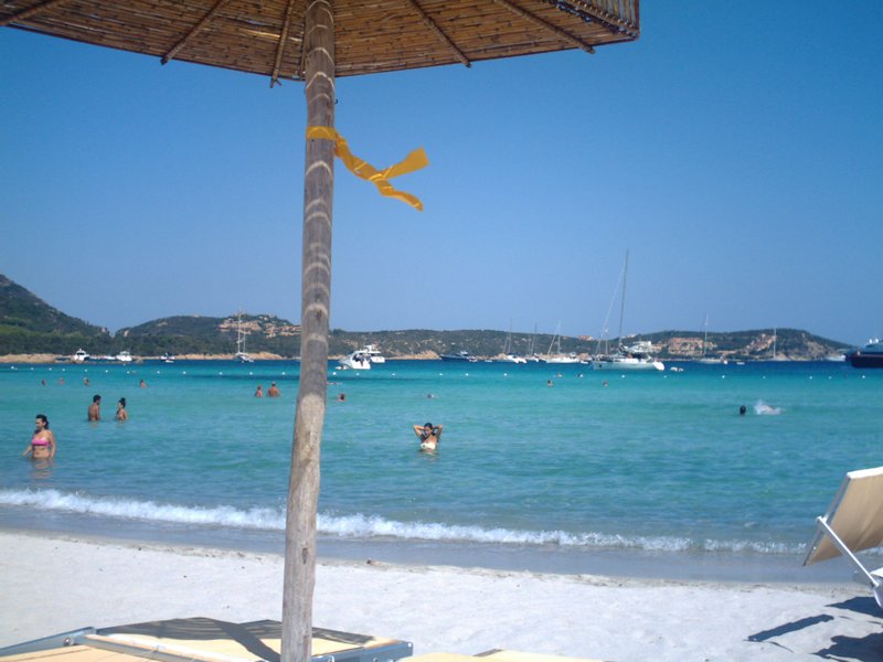 Turquoise water and a sandy beach along Sardinia's Costa Smeralda, with yachts anchored offshore