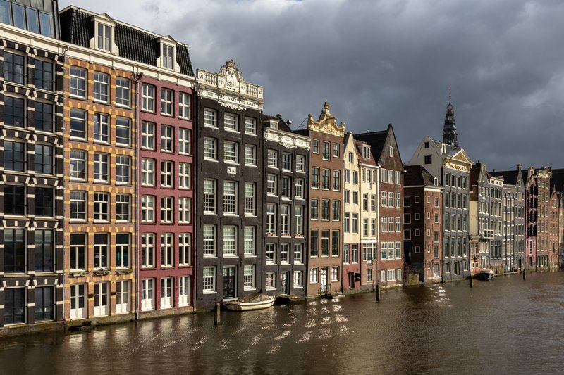 Colorful canal houses reflected in the water at golden hour in Amsterdam