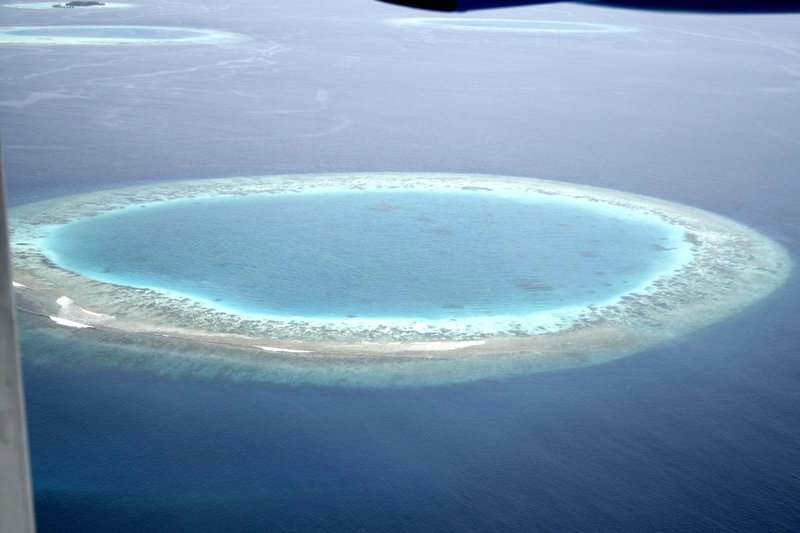 View of a Maldives island from a seaplane, surrounded by lagoon