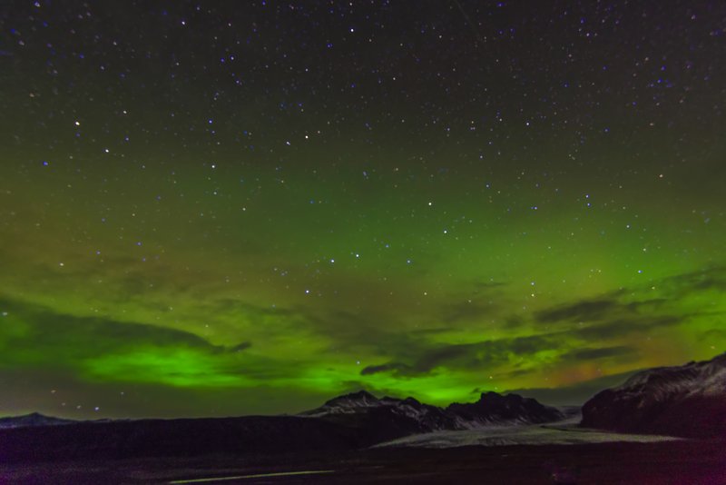 Aurora borealis over a glacier and mountains in Iceland