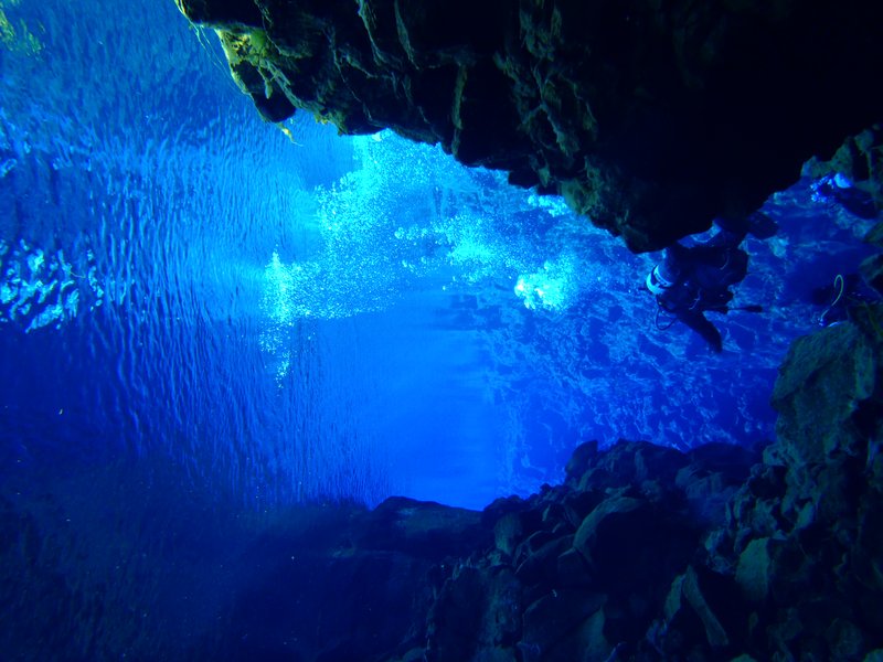 Diver's bubbles rising through the crystal-clear rift walls of Silfra fissure