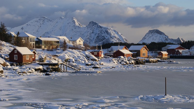 A snow-covered fishing village on the frozen shore beneath Lofoten's peaks