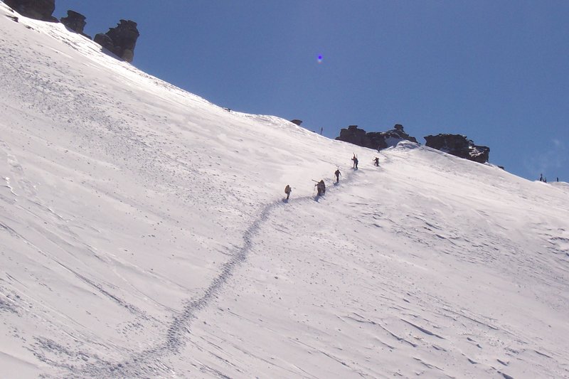Backcountry skiers climbing a ridge above Treble Cone's off-piste terrain