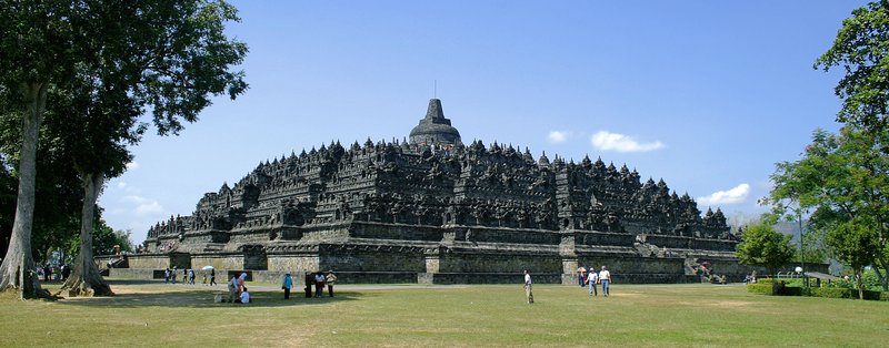 Borobudur temple's stupa-studded terraces with misty volcanic peaks behind