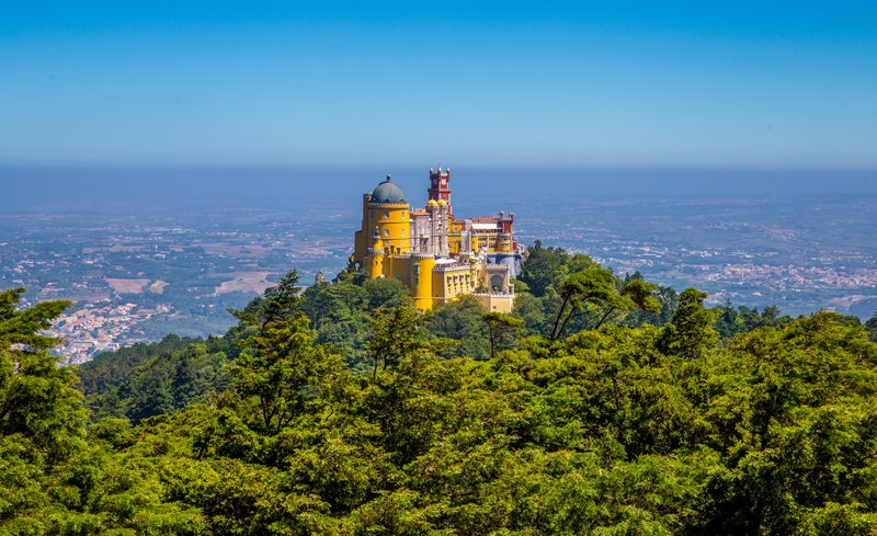 Pena Palace in vivid colours atop a forested peak in Sintra
