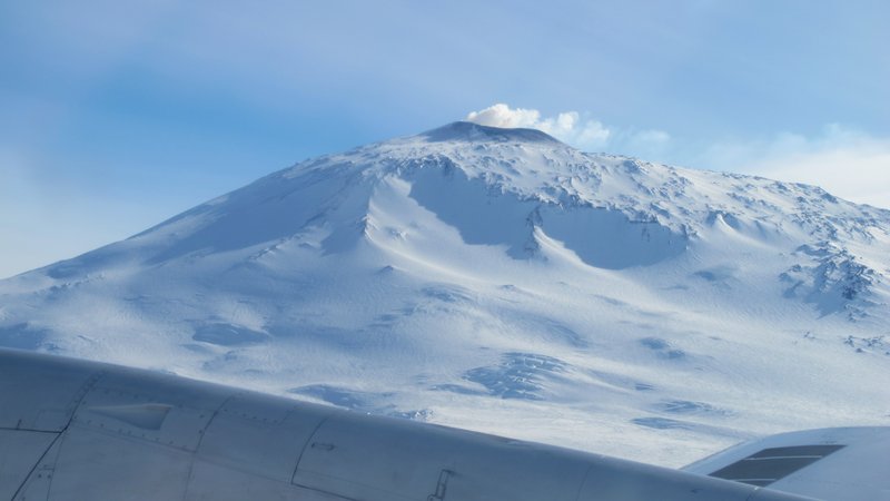 Aerial view of Mount Erebus rising from the Antarctic ice with volcanic plume