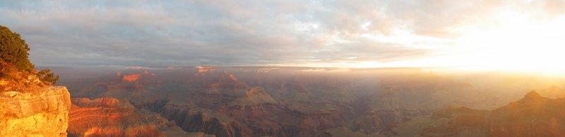 Panoramic view across the vast layered rock formations of the Grand Canyon at dawn